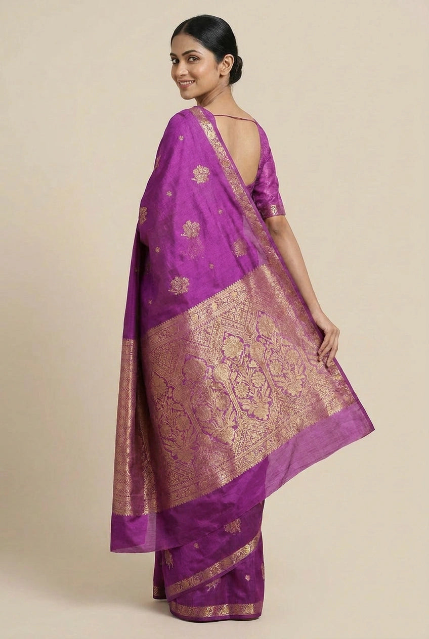 Woman wearing a purple saree with gold patterns on a beige background