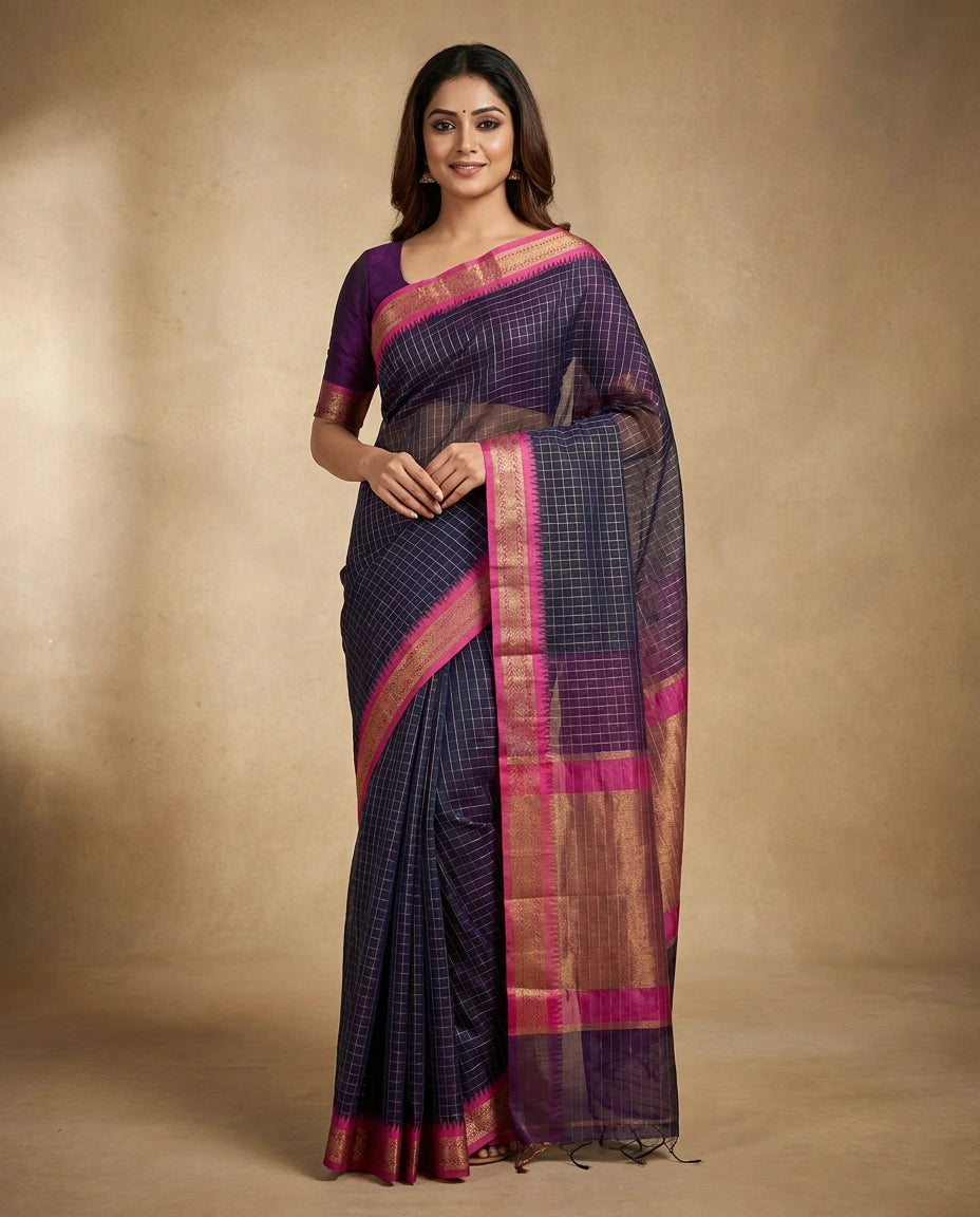 Woman wearing a dark blue saree with pink and gold border against a beige background