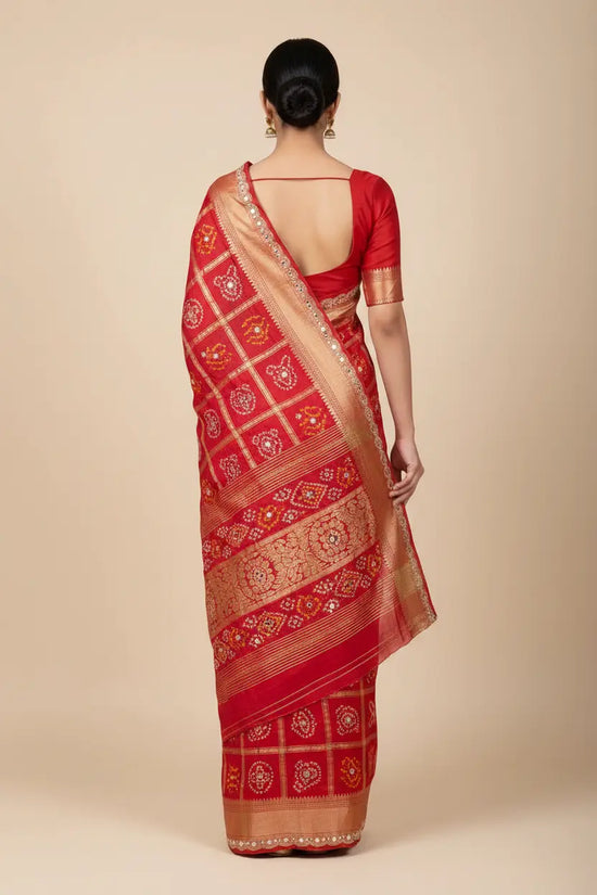 Red saree with gold patterns worn by a person on a beige background