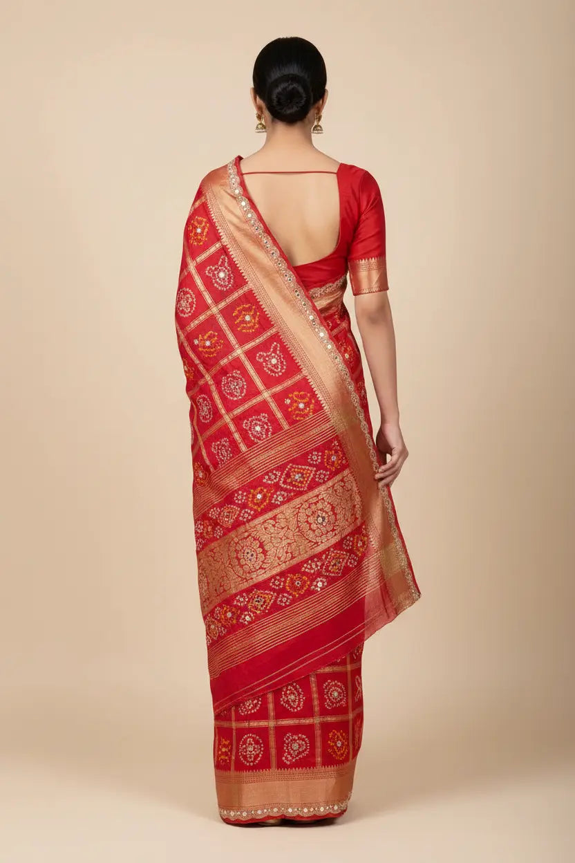 Red saree with gold patterns worn by a person on a beige background