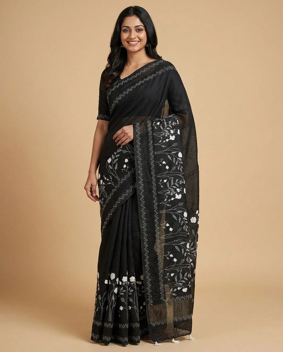 Woman wearing a black saree with white floral patterns on a beige background