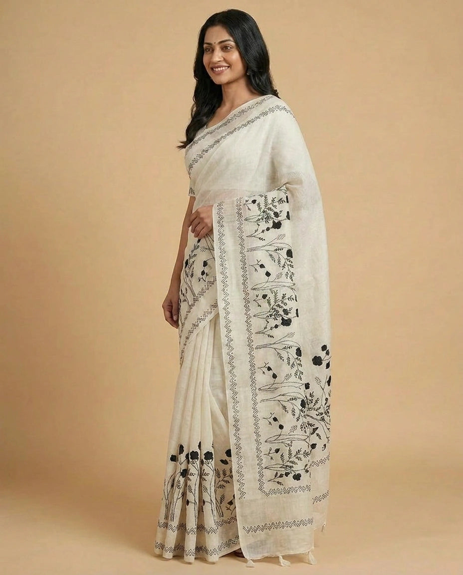 Woman wearing a white saree with black floral patterns on a beige background