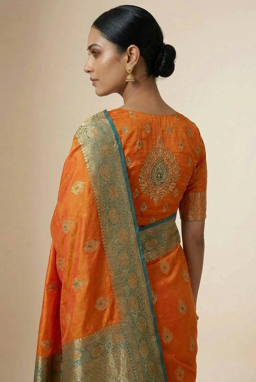 Woman wearing an orange saree with gold embroidery on a beige background