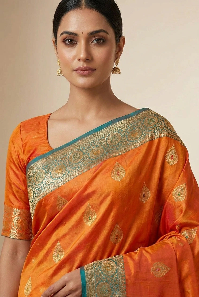 Woman wearing an orange saree with a green border against a beige background