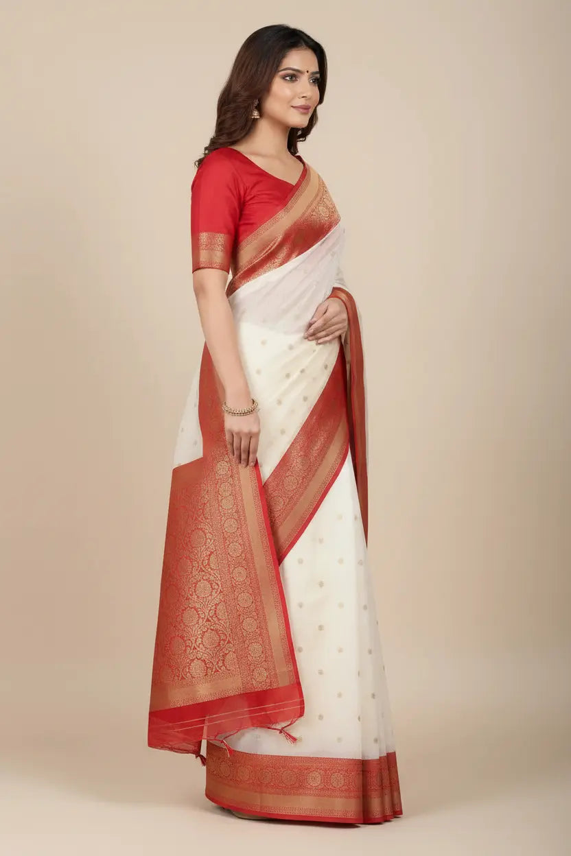 Woman wearing a white saree with red border and blouse on a beige background