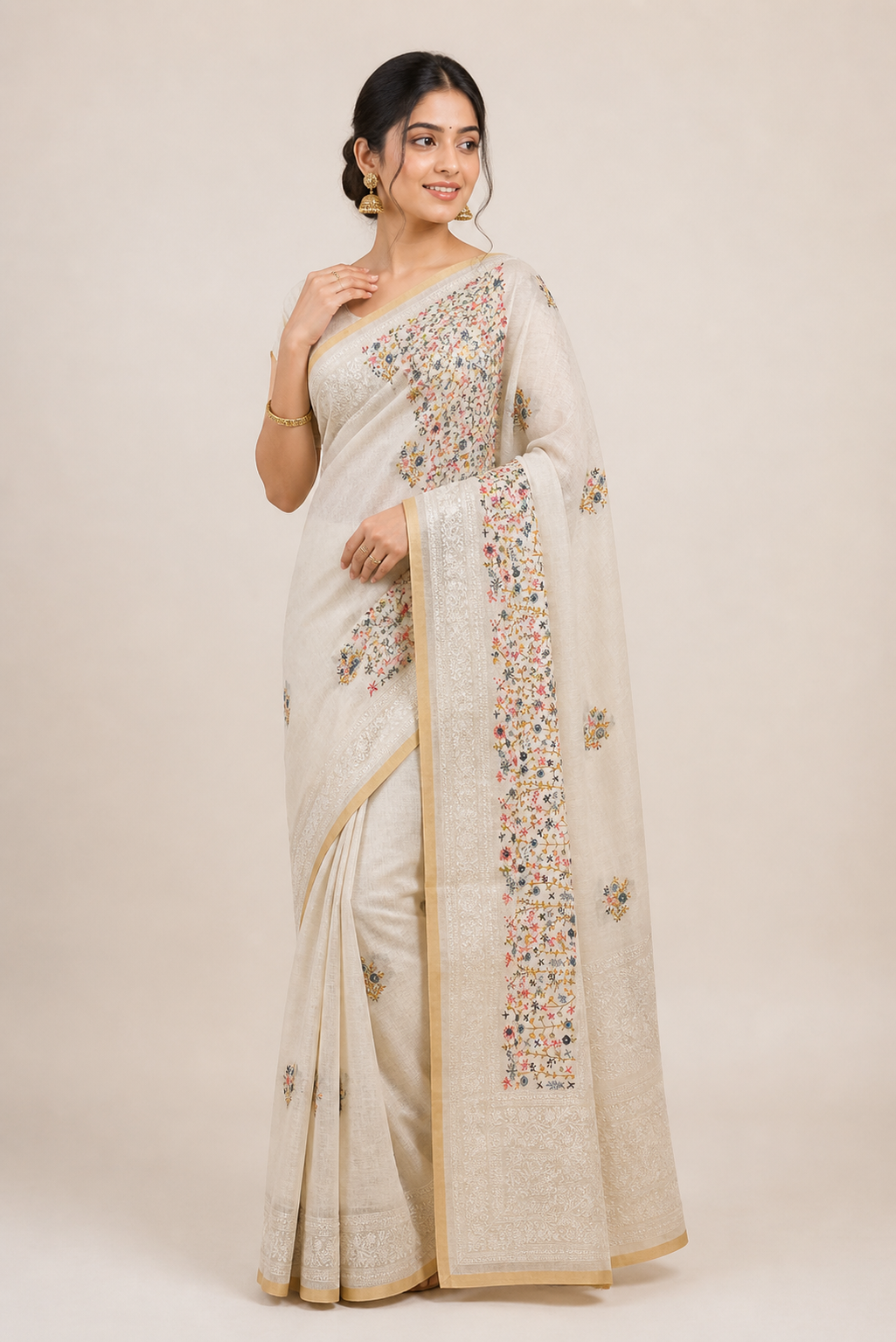 Woman wearing a white saree with intricate designs on a plain background
