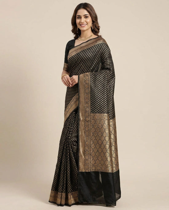 Woman wearing a black and gold saree with a plain background