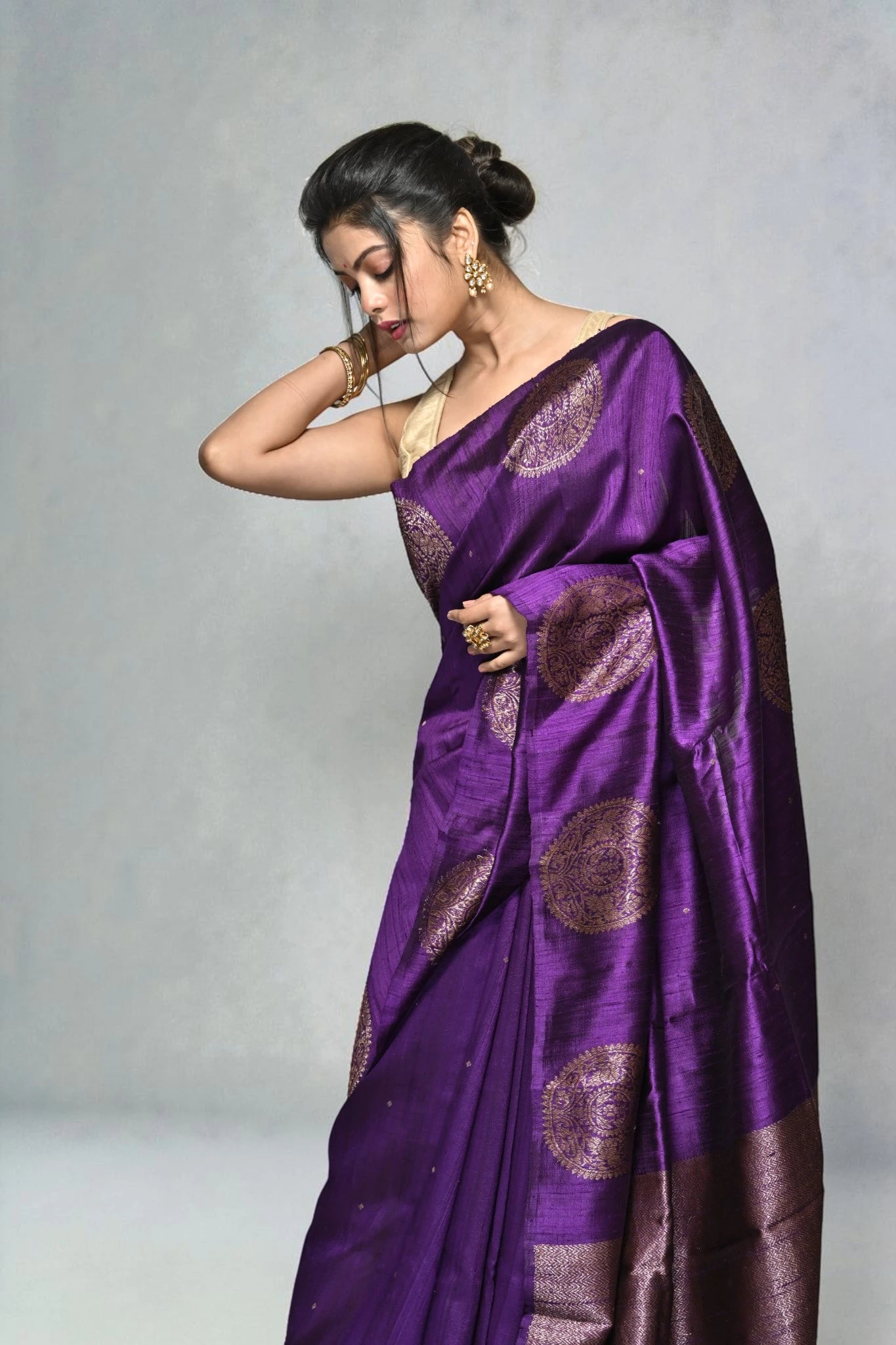 Woman wearing a purple saree with a gray background