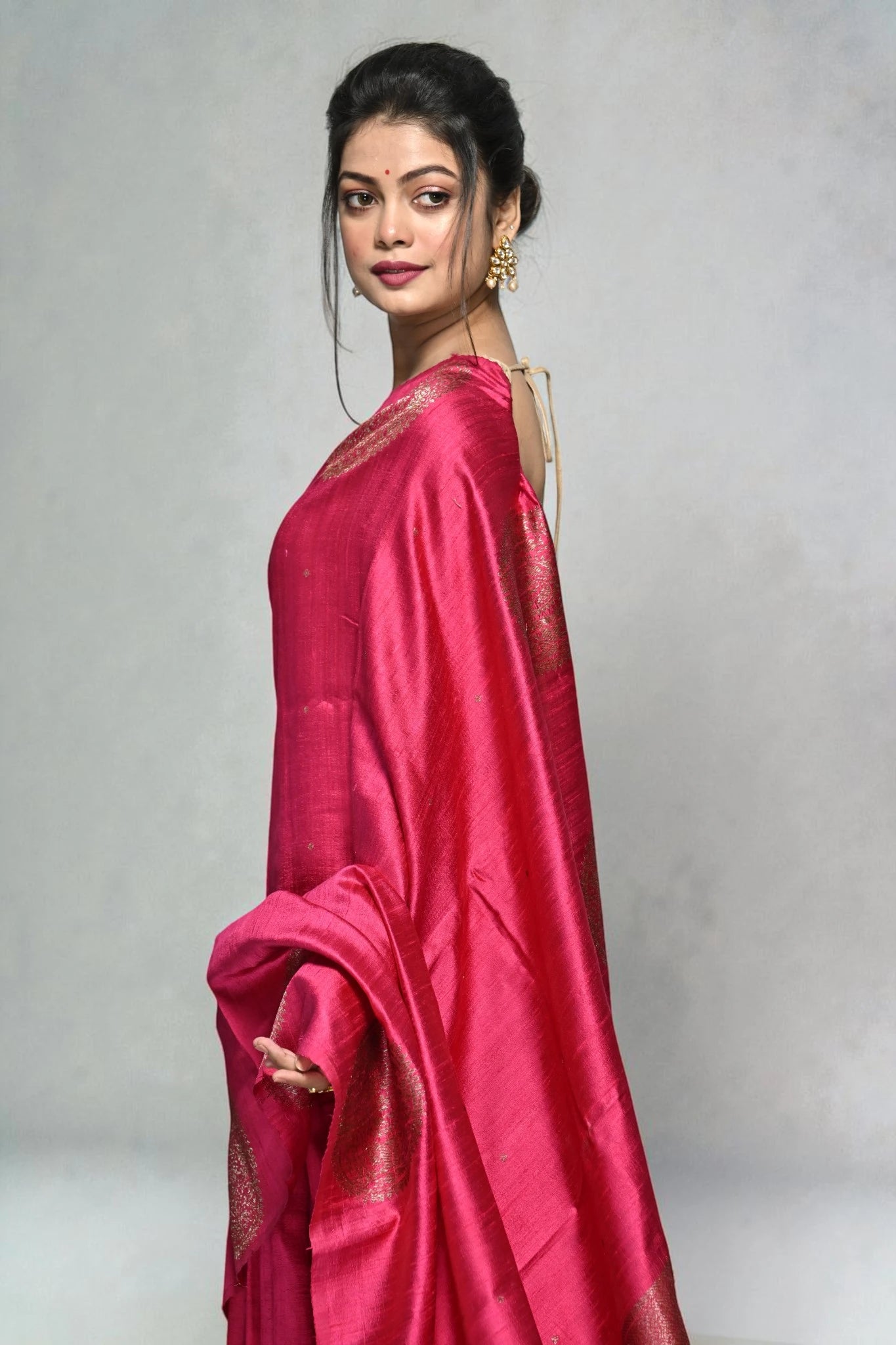 Woman wearing a pink saree with a plain background