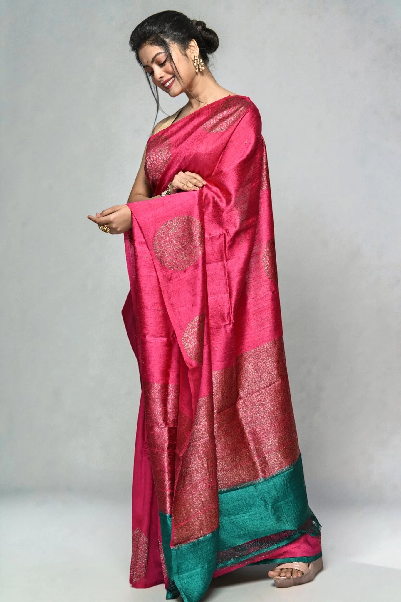 Woman wearing a pink saree with a green border on a white background