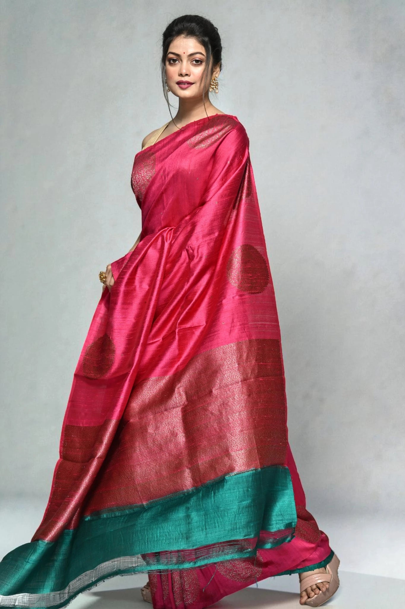 Woman wearing a pink and green saree on a plain background