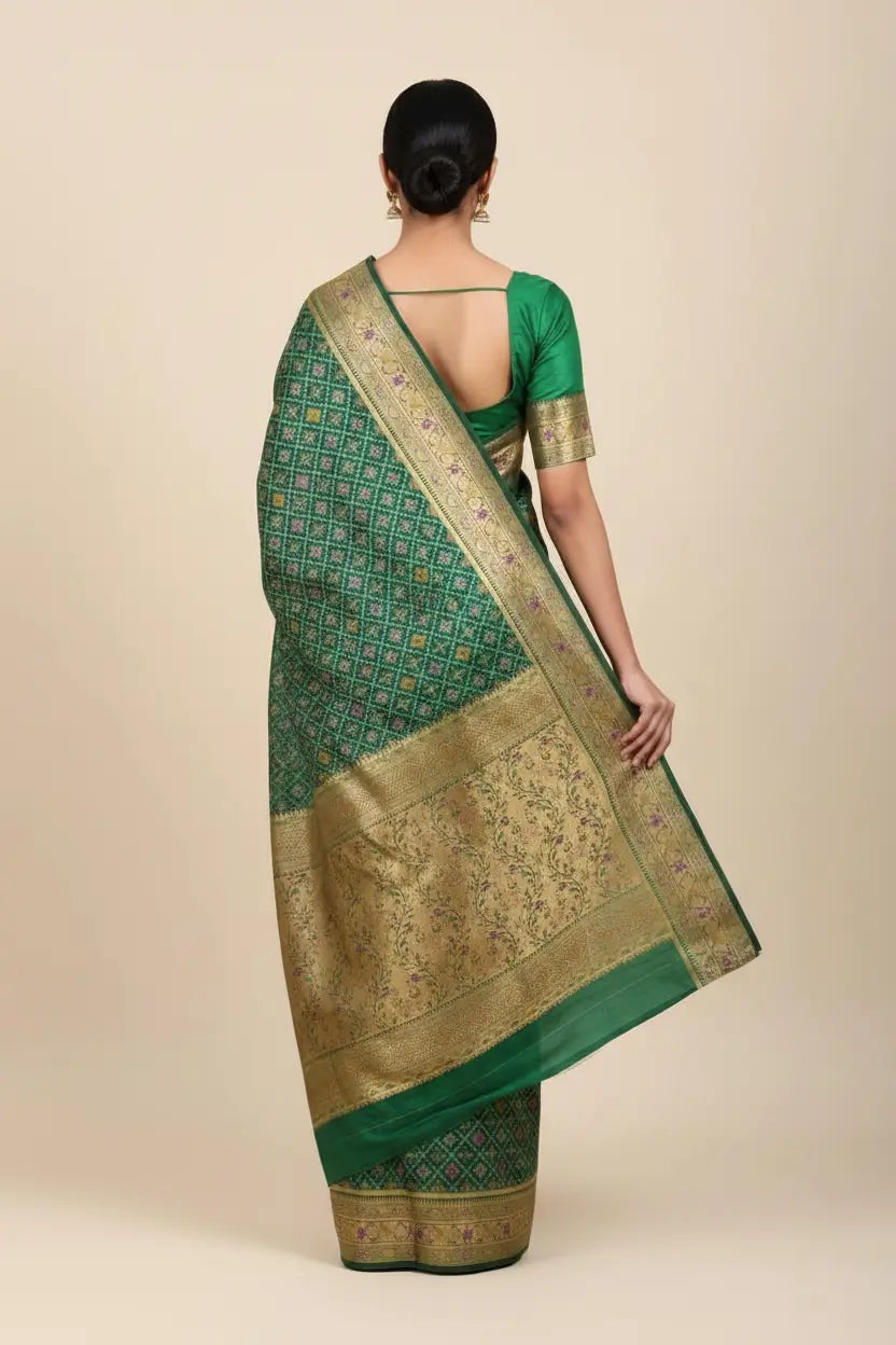 Green saree with gold border worn by a person on a beige background