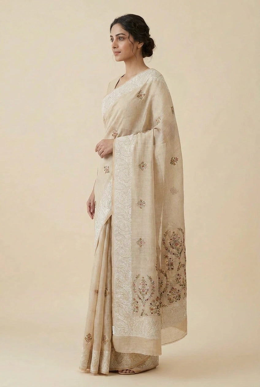 Woman wearing a beige saree with floral patterns against a beige background