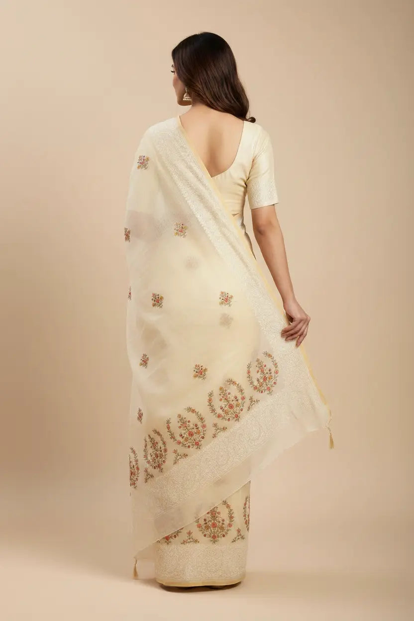 Woman wearing a cream saree with intricate patterns on a beige background
