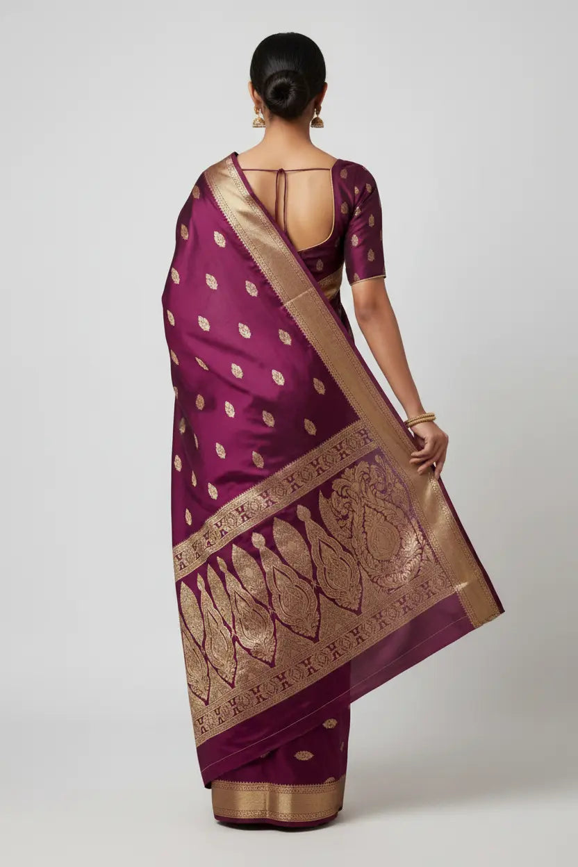 Woman wearing a purple saree with gold patterns on a white background