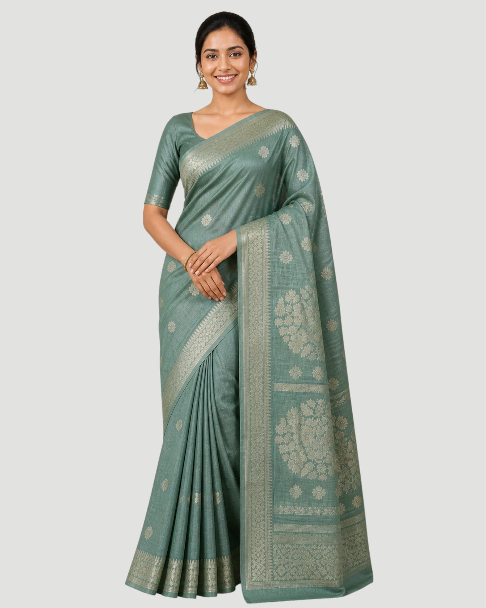 Woman wearing a green saree with a white blouse on a light gray background