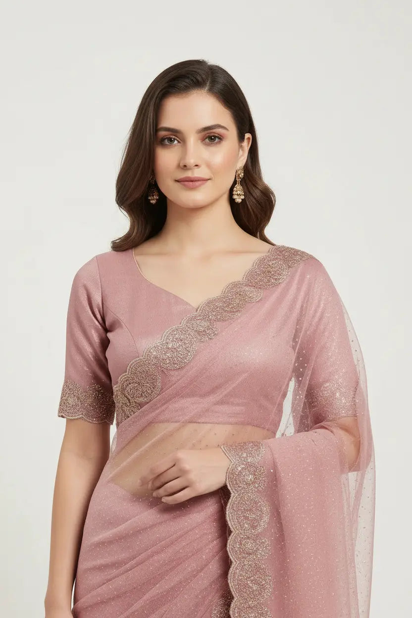 Woman wearing a pink saree with intricate lace details on a white background