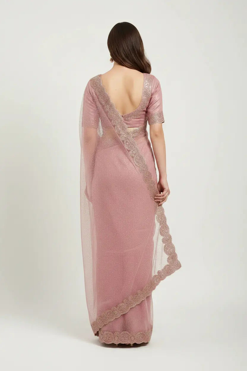 Woman wearing a pink saree with lace details on a white background