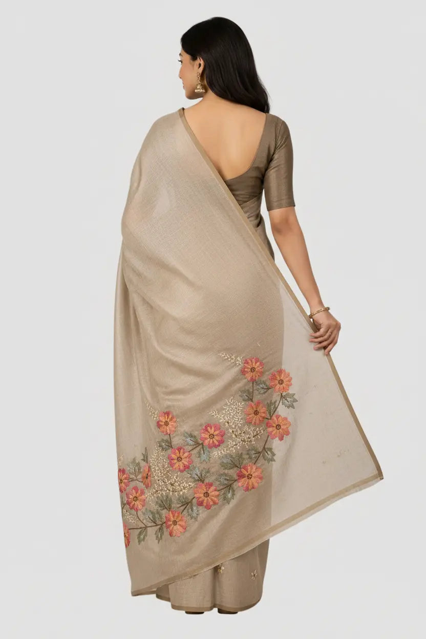 Woman wearing a beige saree with floral embroidery on a white background