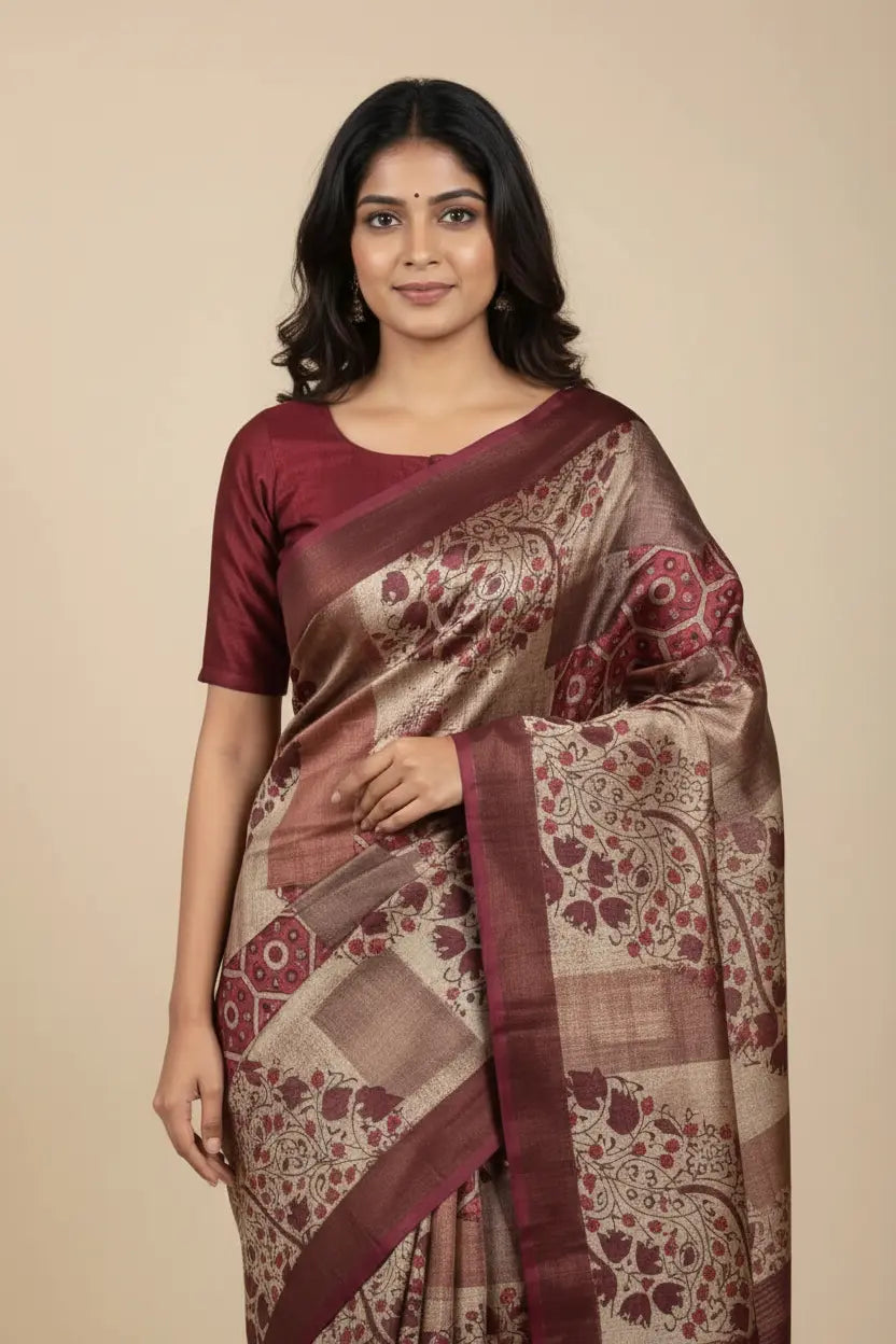 Woman wearing a maroon and beige saree with a floral pattern on a beige background