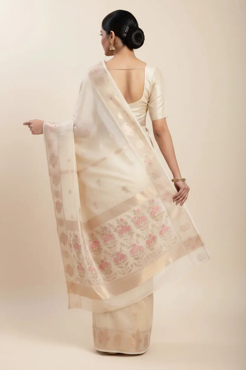 Woman wearing a cream saree with floral patterns on a beige background