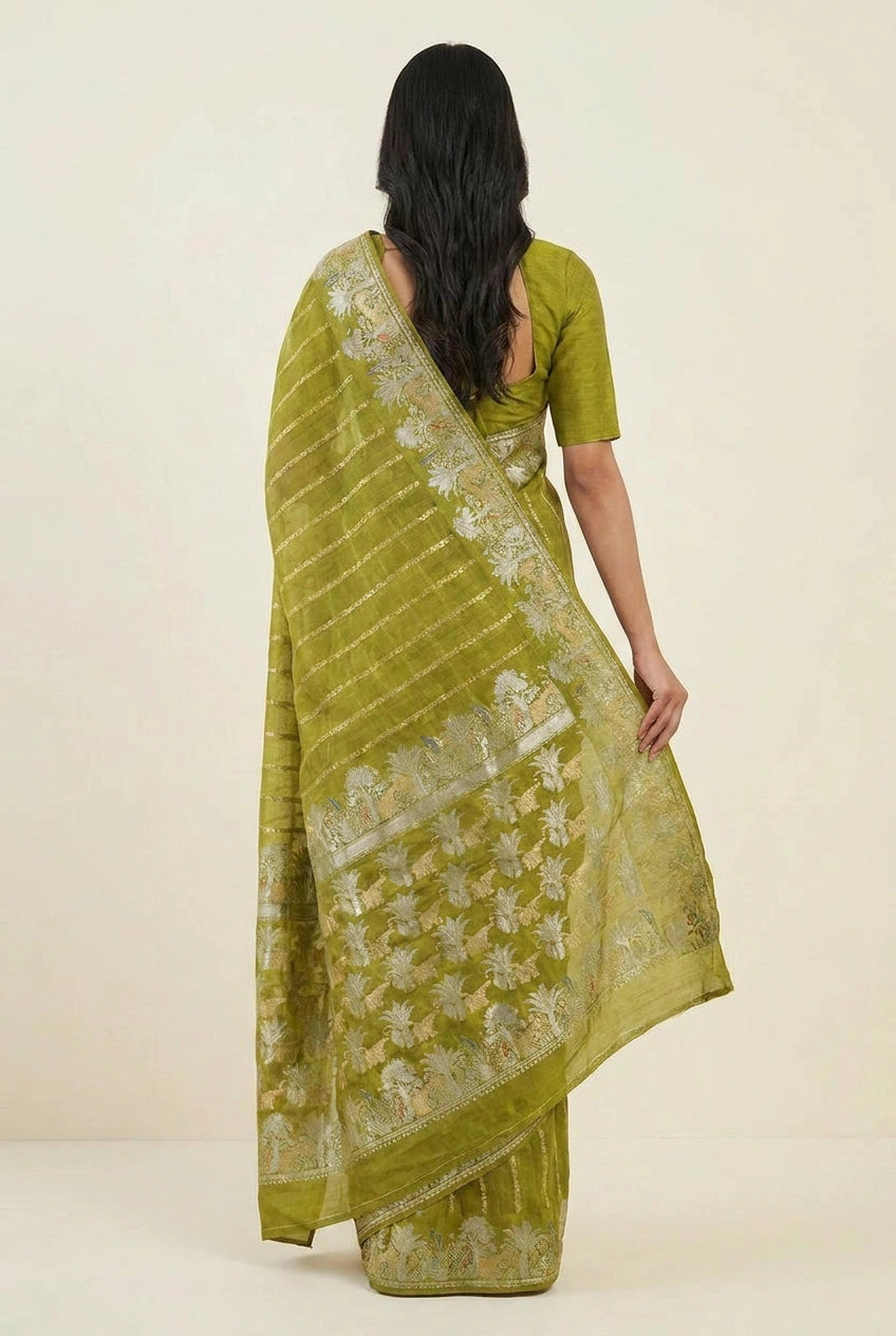 Woman wearing a green saree with a white floral pattern on a beige background