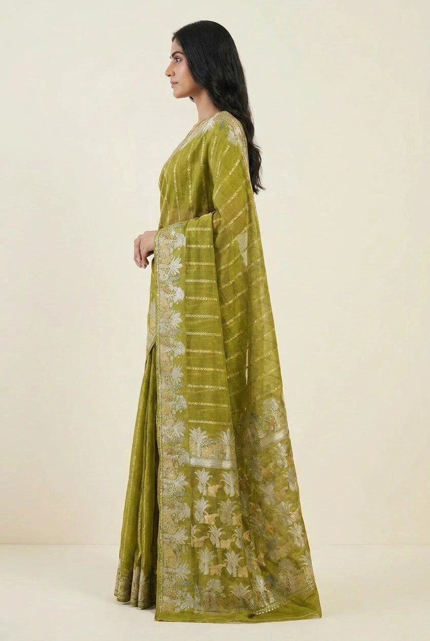 Woman wearing a green saree with a white floral pattern on a beige background