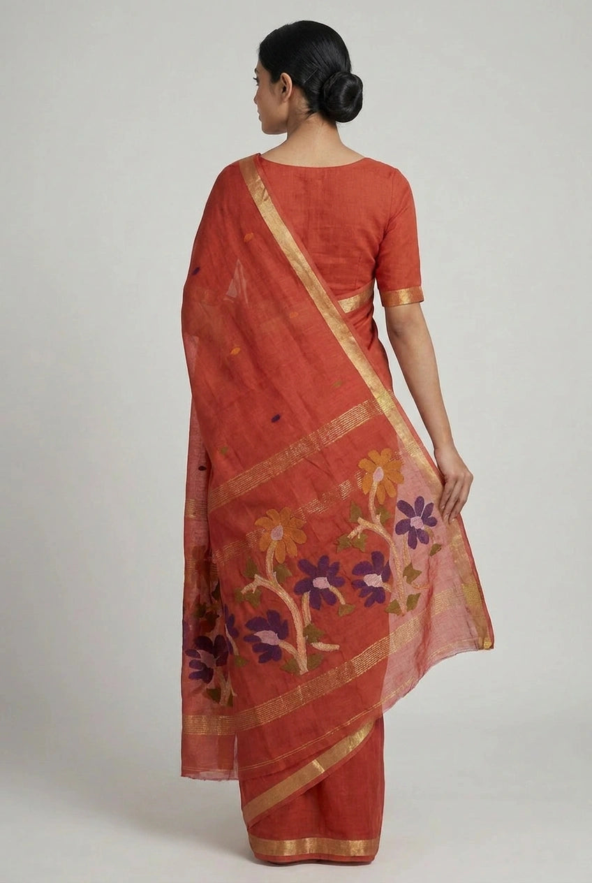 Woman wearing a red saree with floral patterns on a plain background