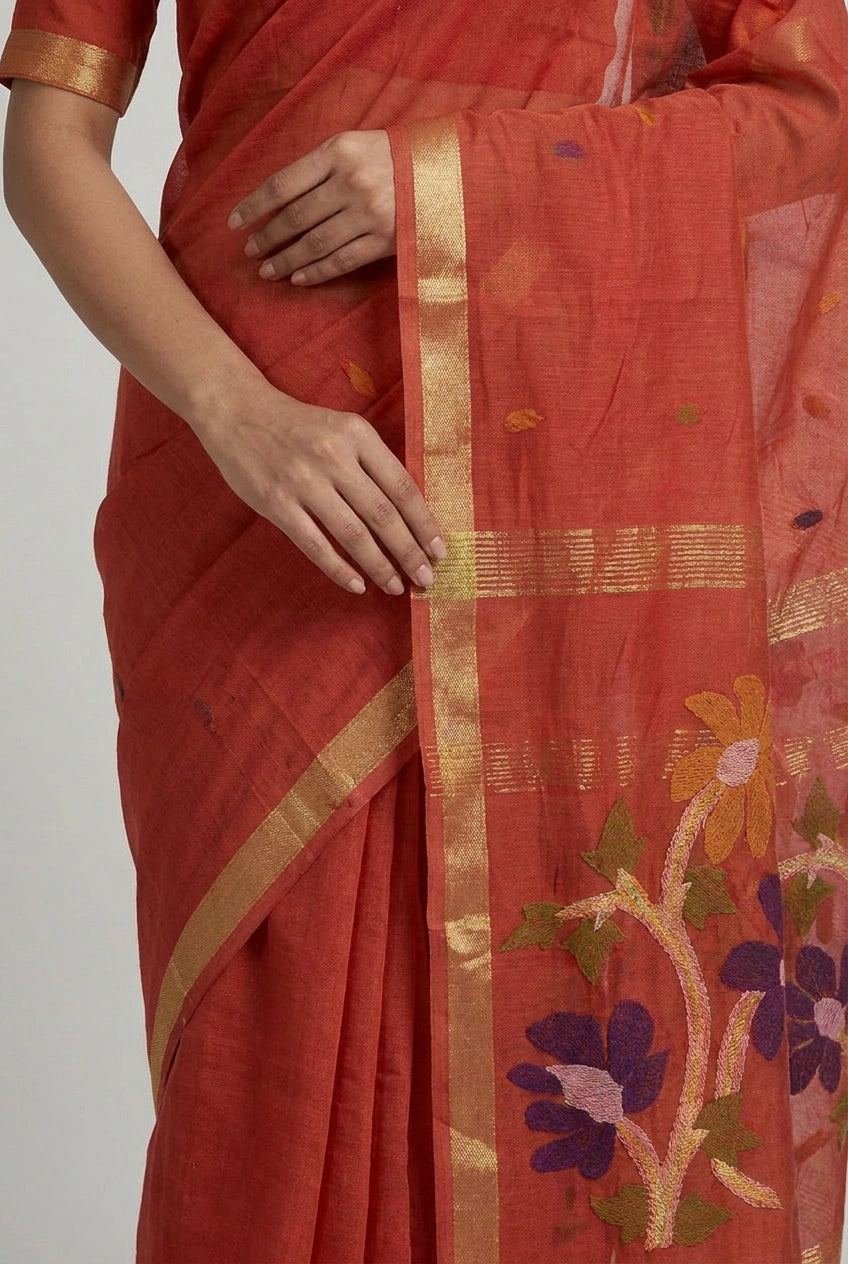 Red saree with floral patterns and a gold border on a plain background