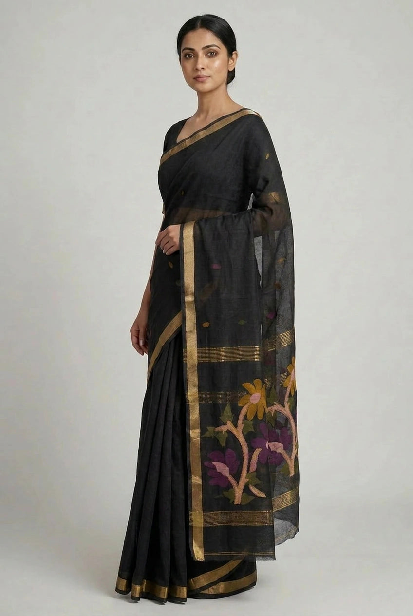 Woman wearing a black saree with floral patterns on a plain background