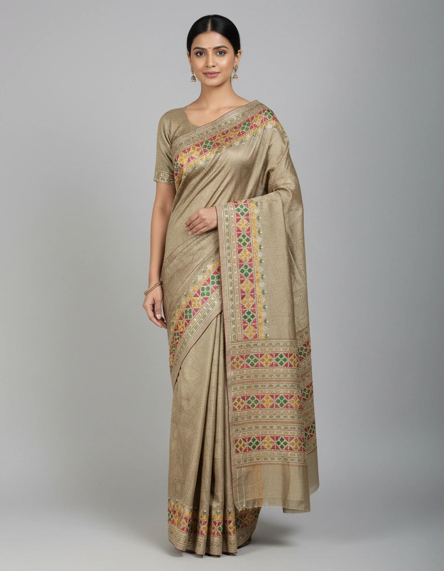 Woman wearing a beige saree with colorful patterns on a gray background
