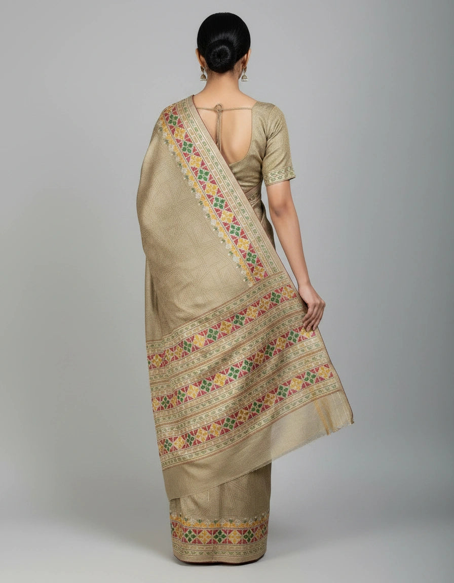 Woman wearing a beige saree with floral patterns on a plain background