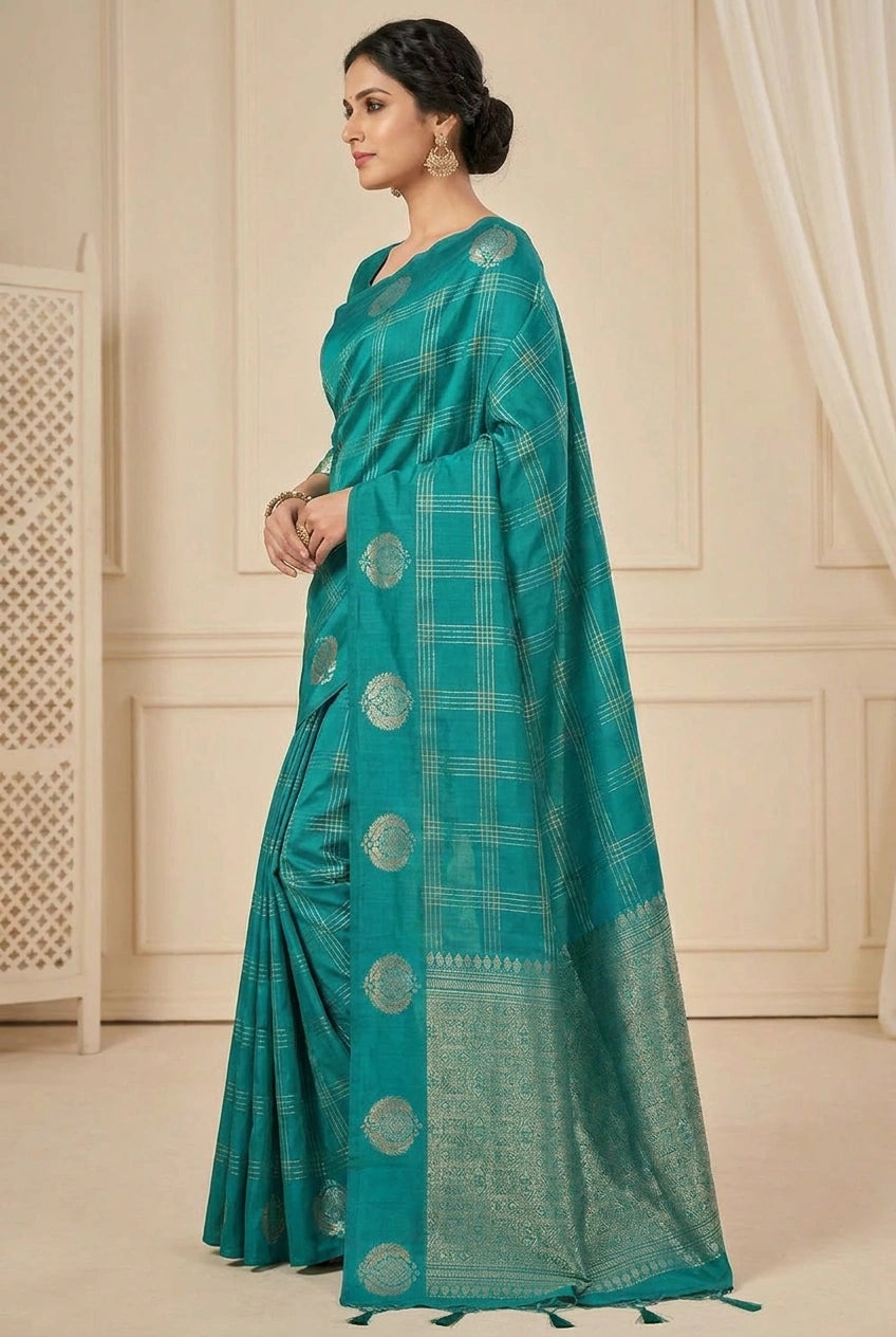 Woman wearing a teal saree with a white checkered pattern indoors.