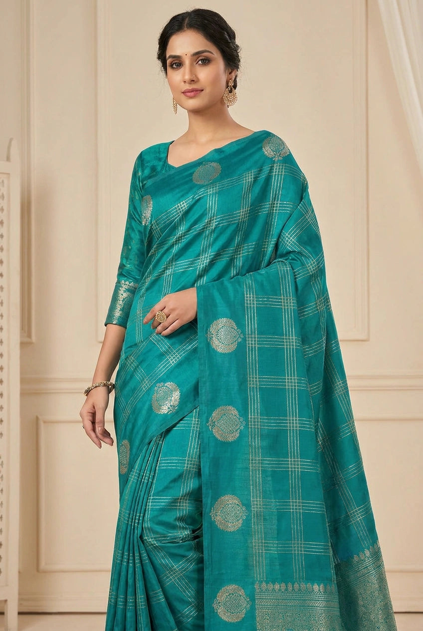 Woman wearing a teal saree with a checkered pattern and circular motifs on a beige background