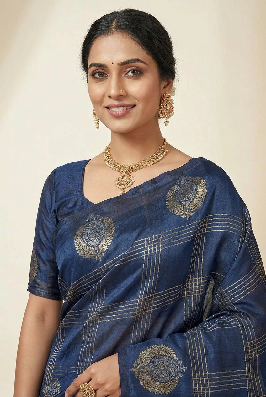 Woman wearing a blue saree with gold patterns on a beige background