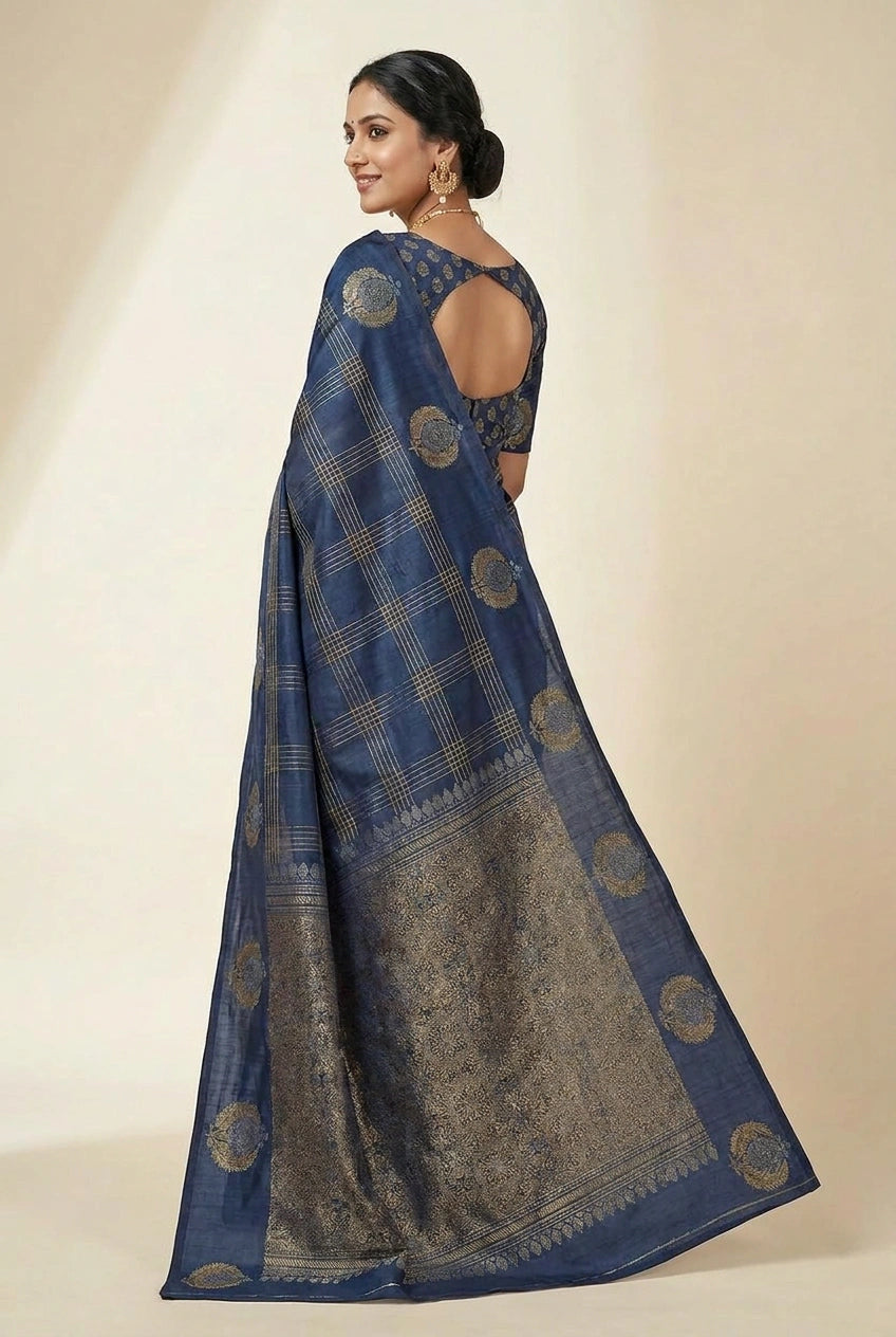 Woman wearing a blue saree with gold patterns on a beige background