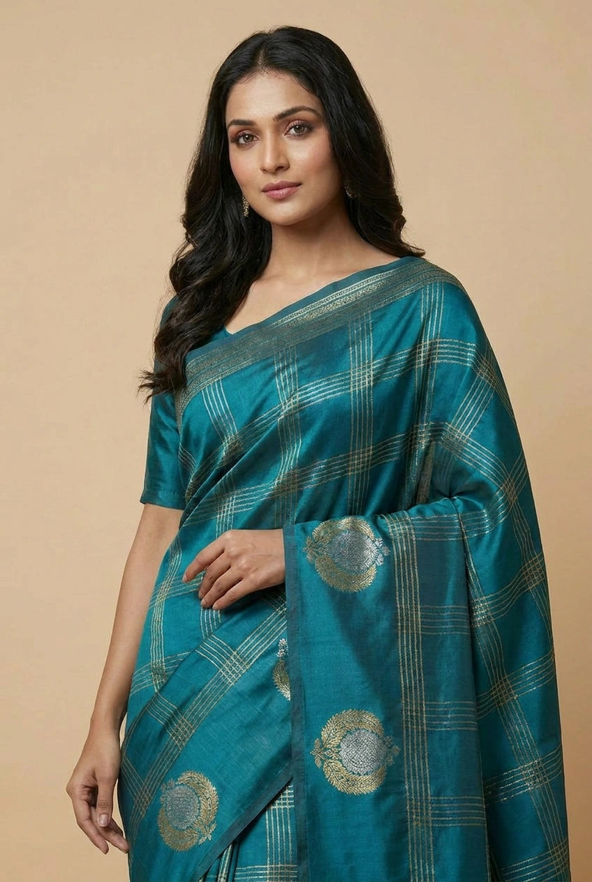 Woman wearing a teal saree with gold patterns on a beige background