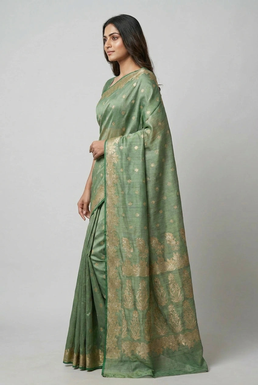 Woman wearing a green saree with a subtle pattern on a plain background