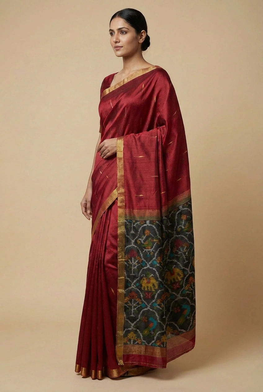 Woman wearing a maroon saree with a patterned border against a beige background