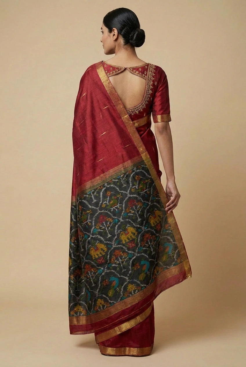 Woman wearing a red saree with a patterned border against a beige background