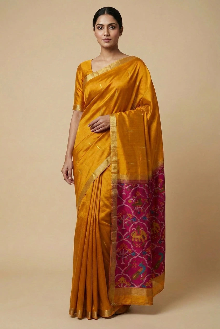 Woman wearing a mustard yellow saree with a pink and gold border on a beige background