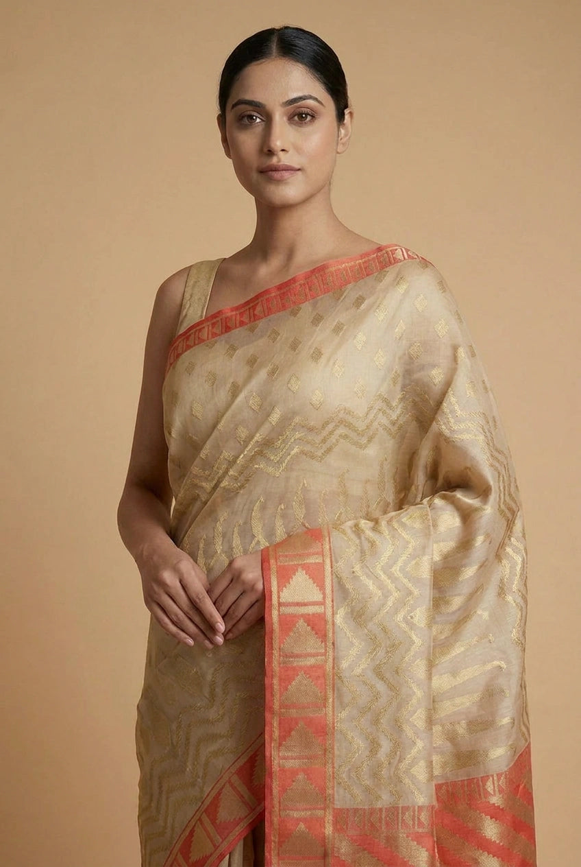 Woman wearing a traditional saree with a beige and red pattern on a beige background