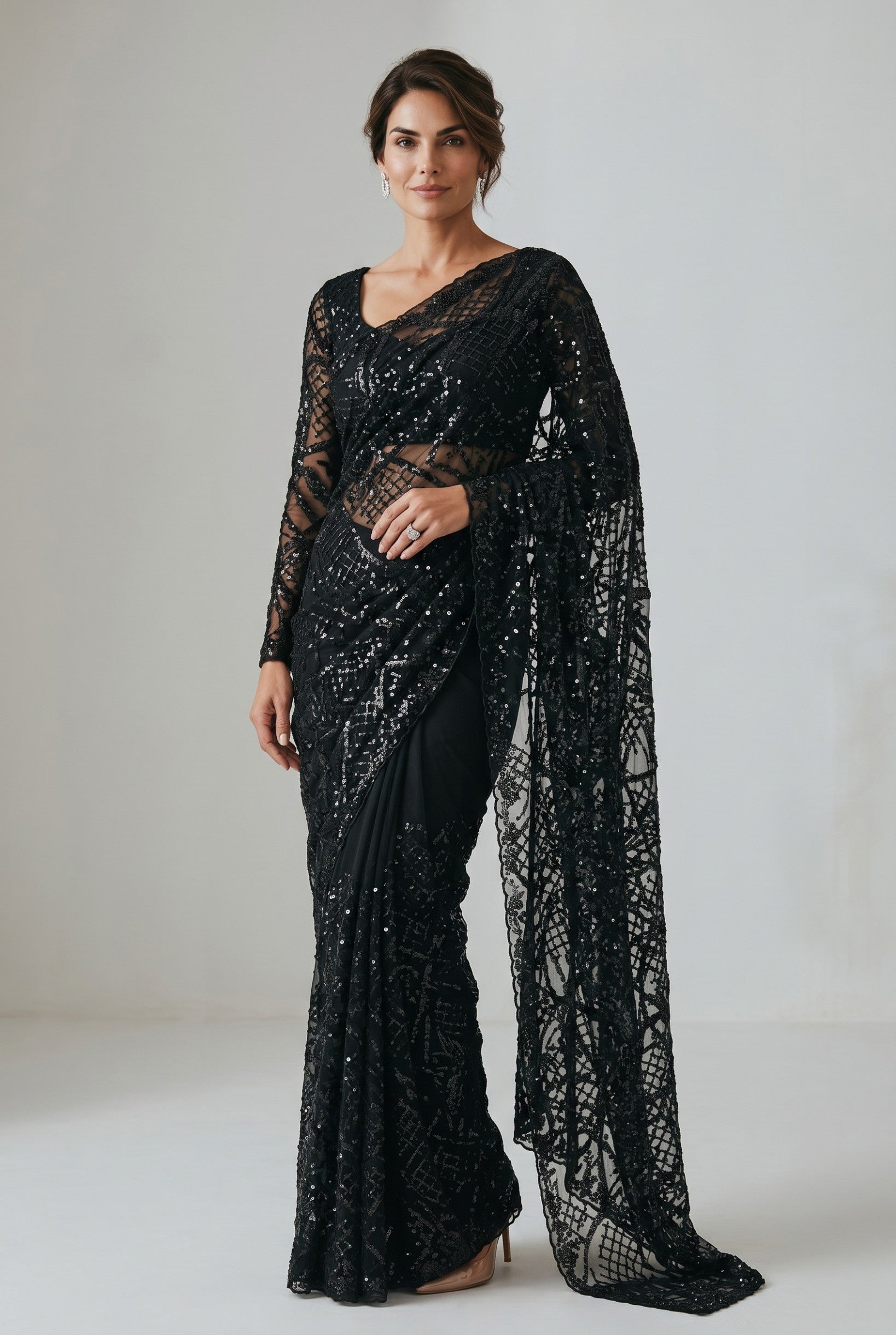 Rangoli black net saree with all-over sequins and statement bell sleeves. Model wears a full-sleeved blouse.