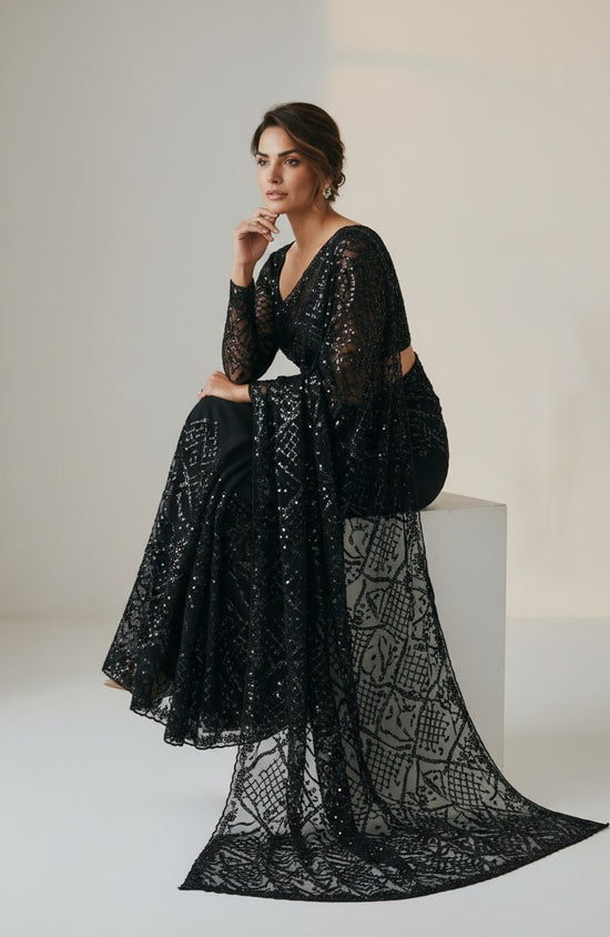 Rangoli black net saree with all-over sequins and statement bell sleeves. Model wears it for a special occasion.