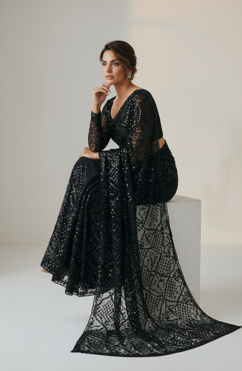Rangoli black net saree with all-over sequins and statement bell sleeves. Model wears it for a special occasion.