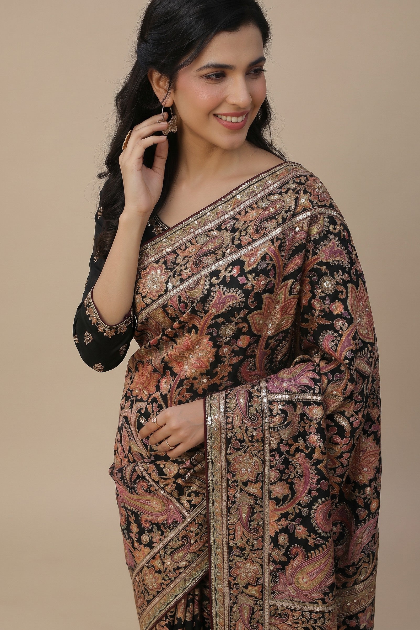 Rangoli black silk saree with pink, orange, and gold paisley embroidery, sequins, and zari work. A woman models the elegant drape.