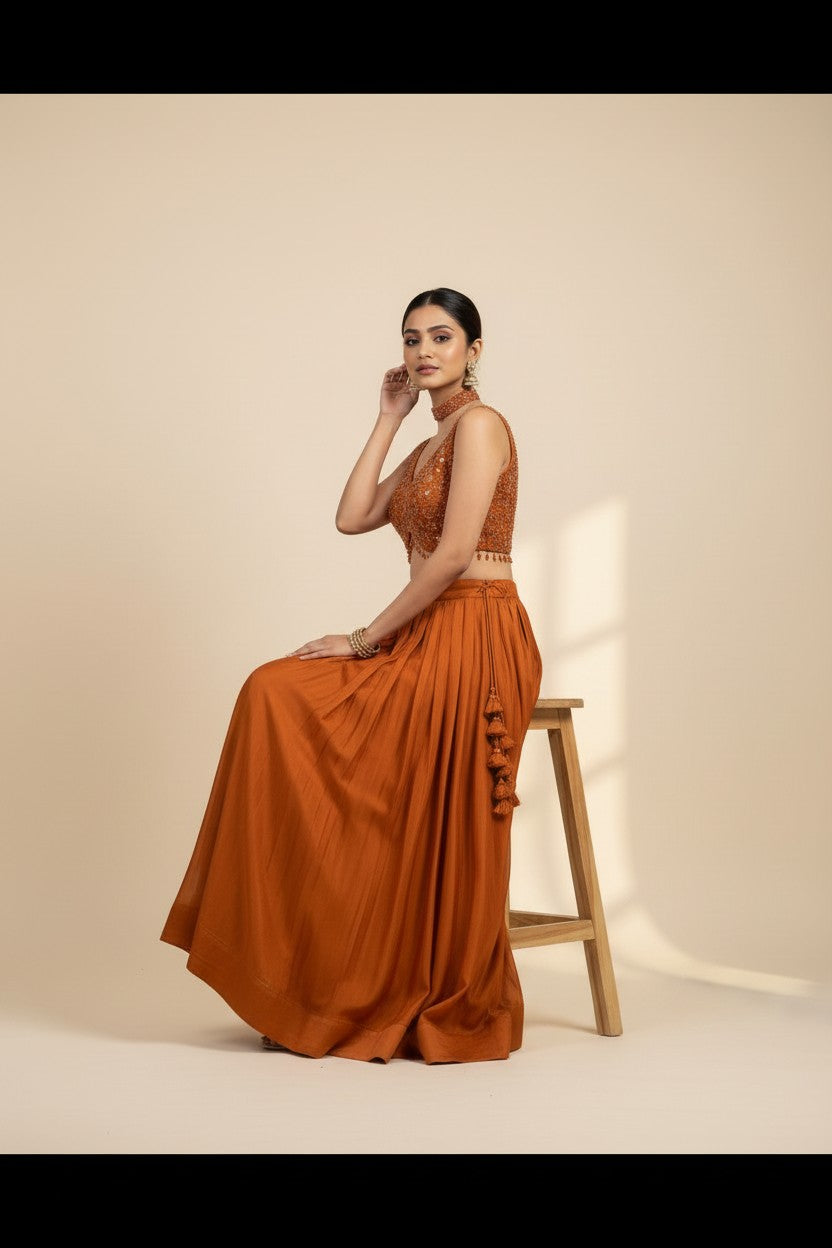 Rangoli burnt orange embellished V-neck sleeveless crop top with pleated lehenga skirt and tassels. Indian ethnic wear.