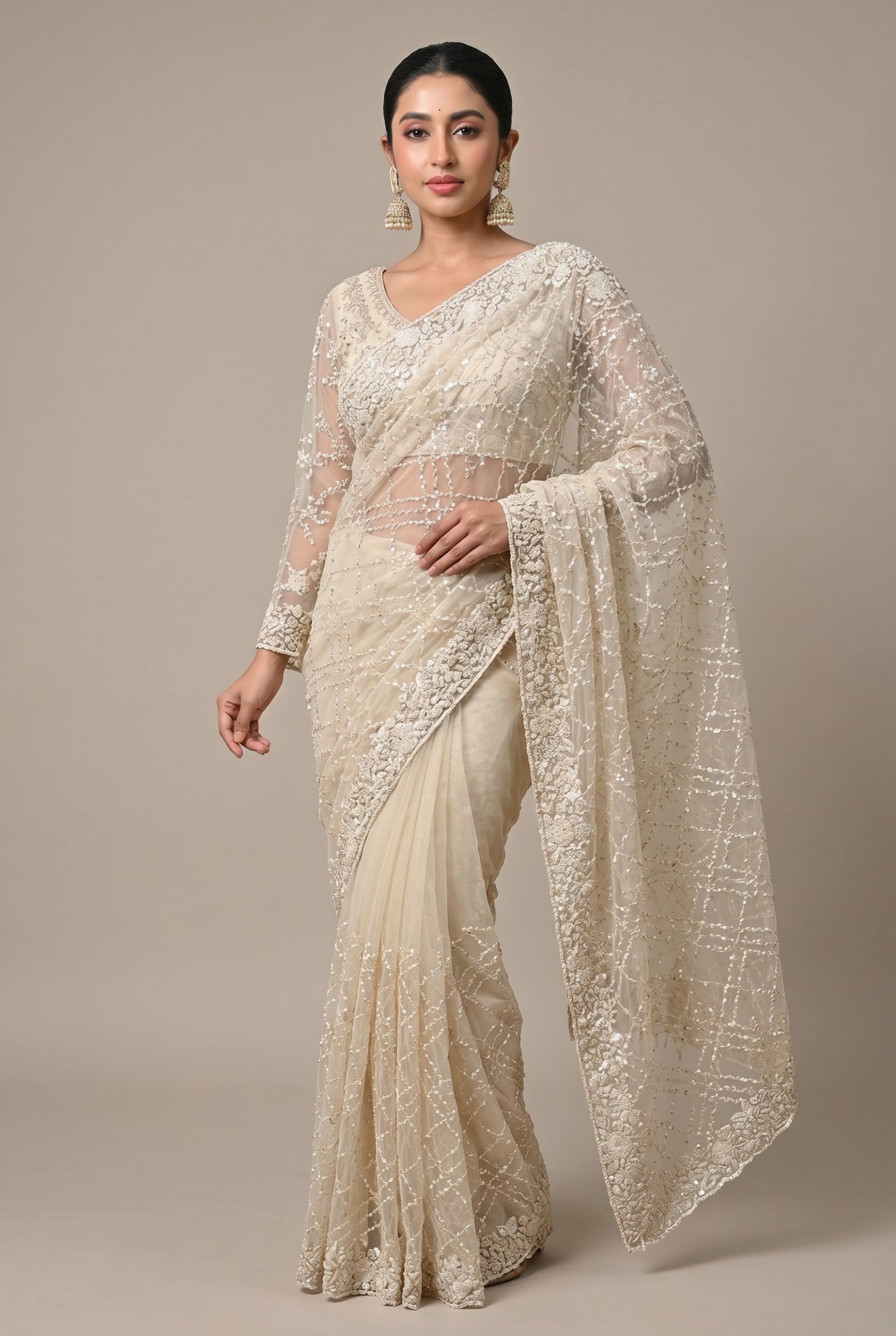 Rangoli cream net saree with full sleeves, intricate embroidery, and sequins. Perfect for festive occasions.