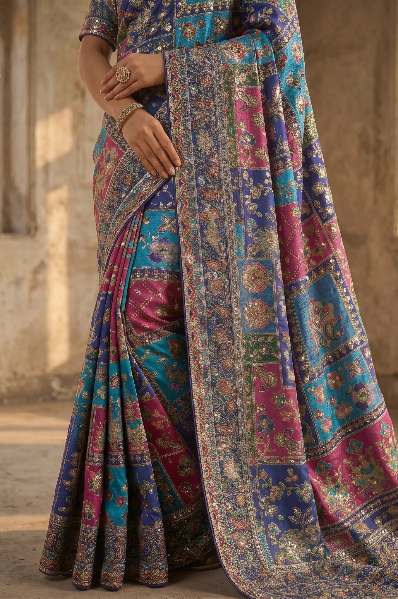 Colorful saree with intricate patterns on a textured wall background