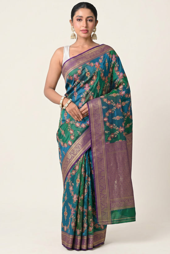 Rangoli teal and emerald green silk saree with floral embroidery, sequins, and purple border with gold motifs.